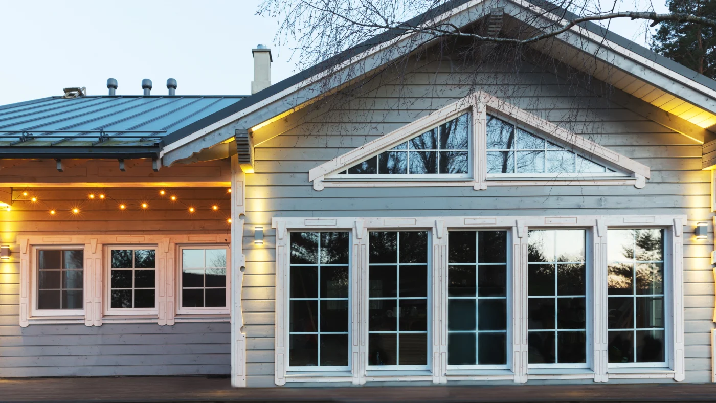 Home front with beautiful large windows with white frames and handing string lights over them