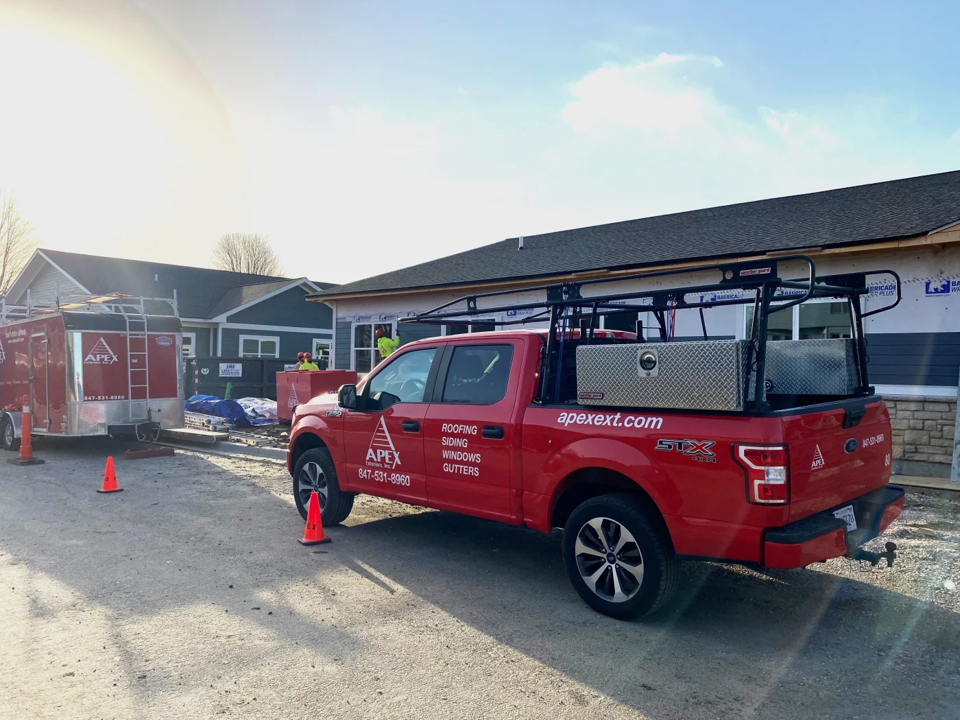Apex Exteriors service truck and trailer parked at a job site for a multi-unit building, showcasing the company’s long-standing experience and hands-on expertise with gutter systems for Chicagoland multi-family properties.