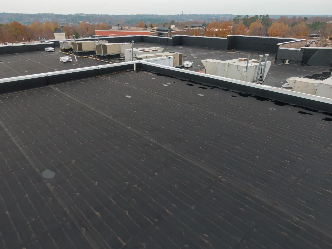 An image taken on top of a large commercial building’s roof with a newly-installed EPDM roofing system, all black, with some wet spots after it rained.