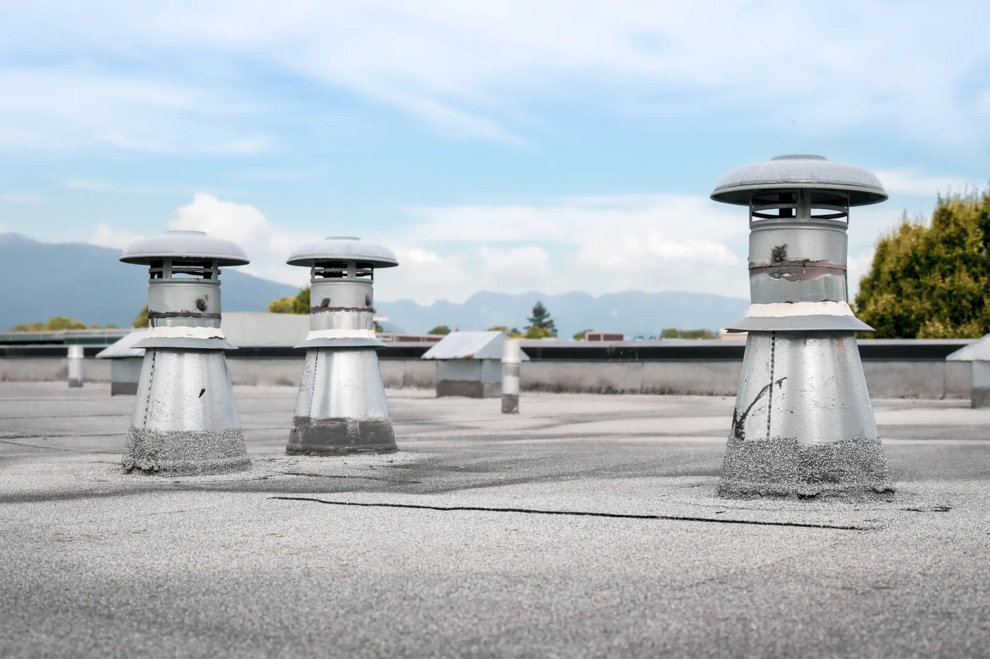Close-up on a section of a flat commercial roof with vents showing and a newly-installed modified bitumen roofing system.