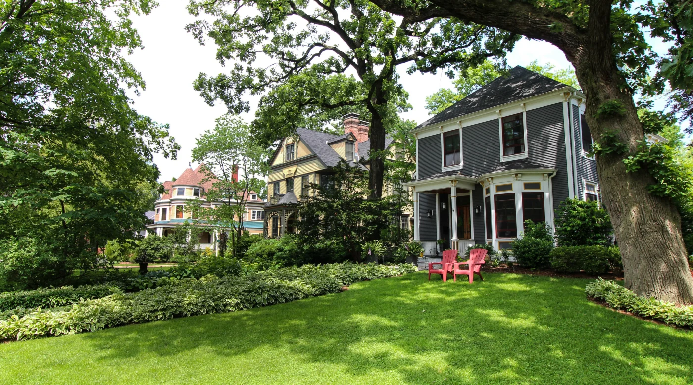 Three lovely homes in the Oak Park area of Chicagoland with different siding types and colors, unique architecture, various kinds of windows and entryways, roofing styles, and lush landscaping in the summertime.