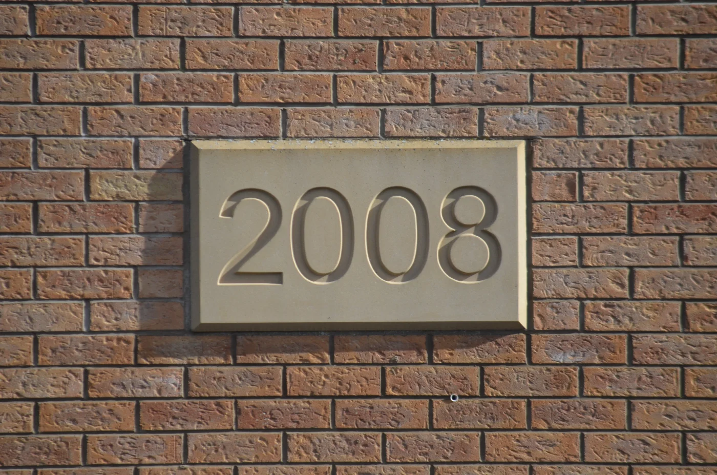 A brick wall with a plaque showing the year 2008.