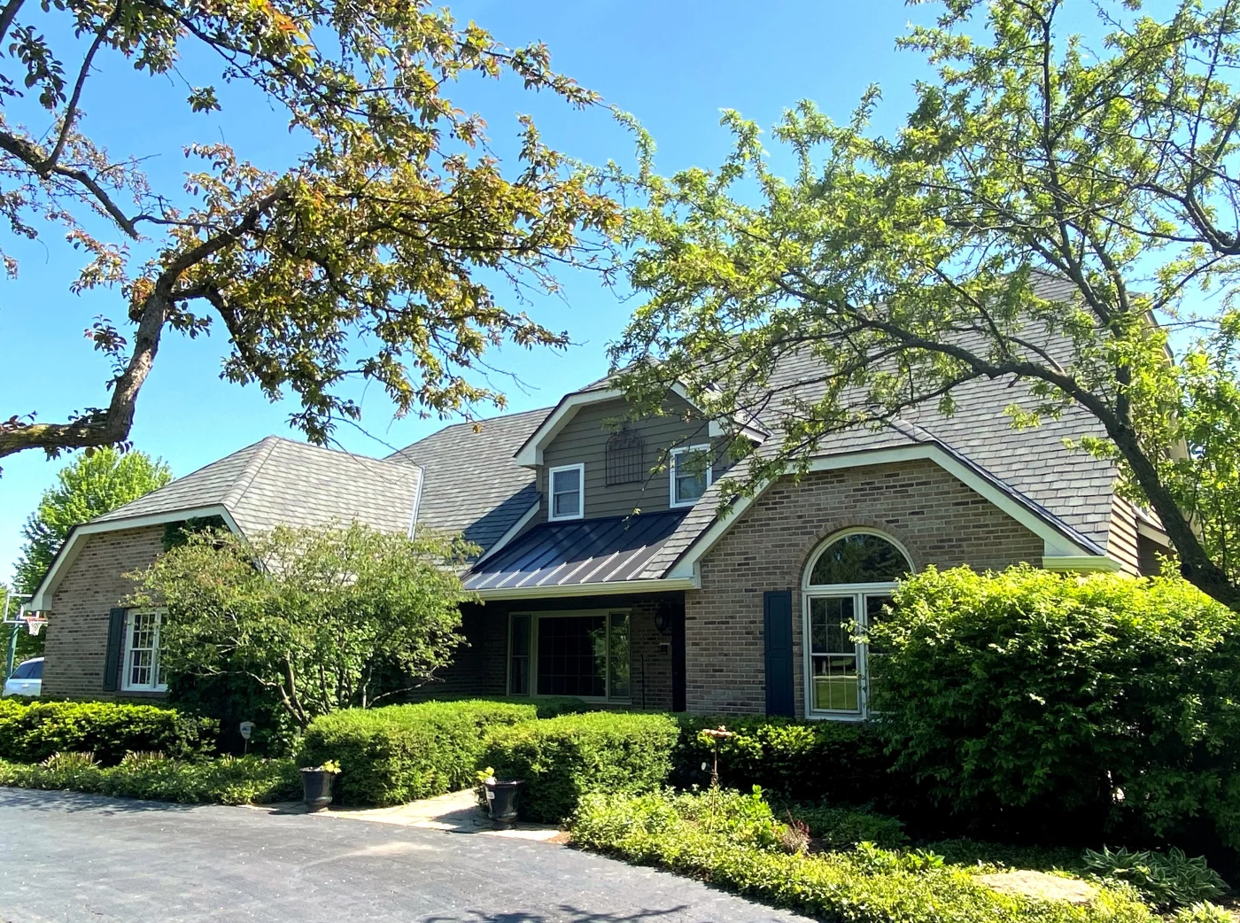Good, Better, Best Selection Of Exterior Remodeling Products A two-story brick home in Chicagoland, large with three main sections with beautiful white windows, and new roofing and siding installed by Apex Exteriors.