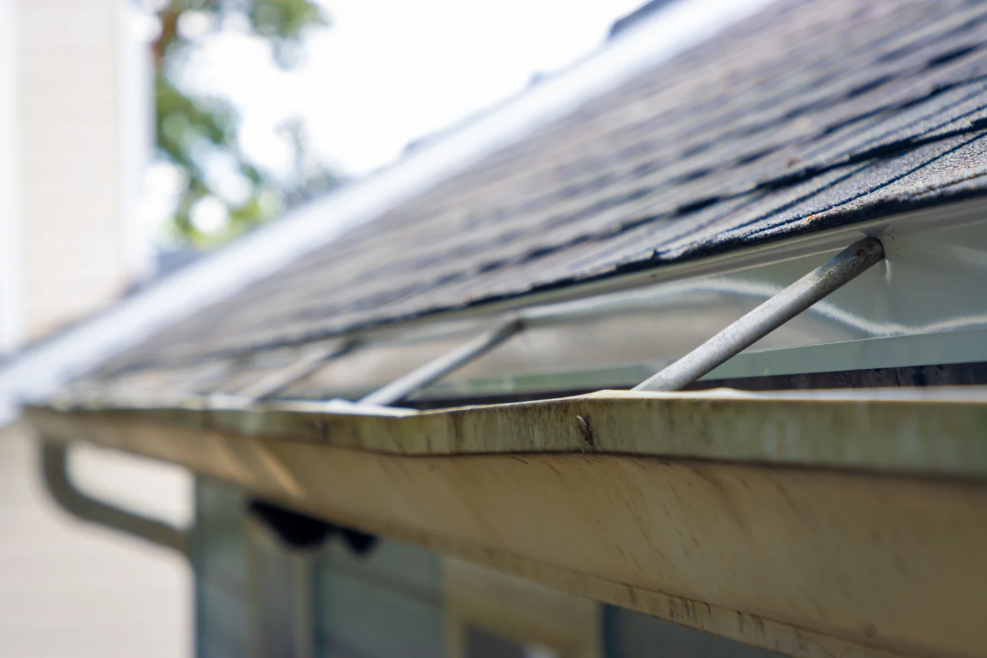 A close-up of old, outdated gutters showing rust and deformation.