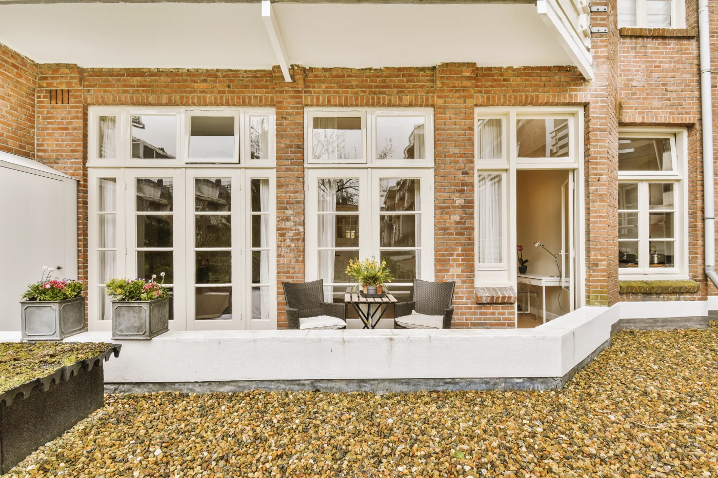 The image features the back of a brick home with amazing, large, white framed windows.