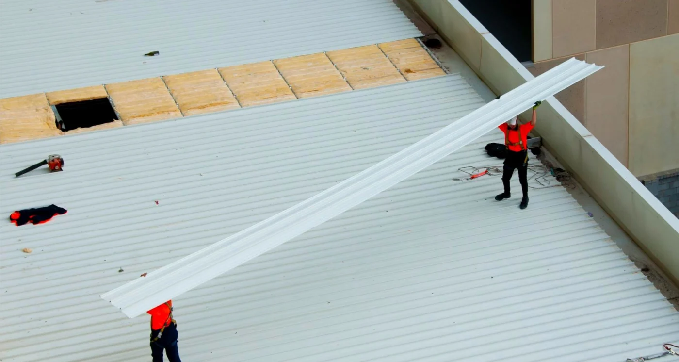 Image of two men laying metal on a commercial rooftop