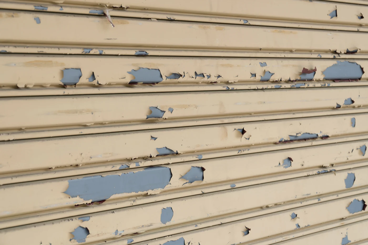Close-up image of old, yellowed, and peeling siding on a building