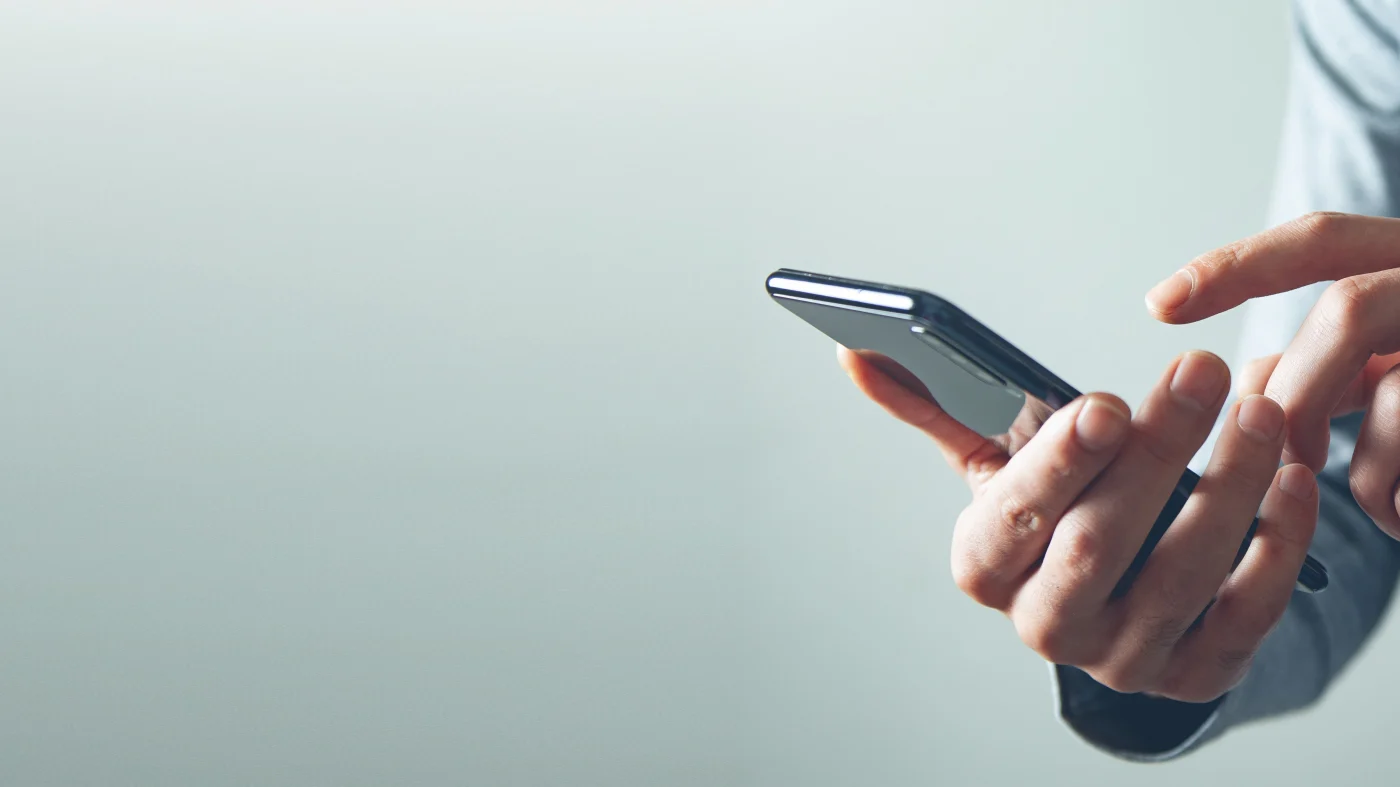 Close-up of a person’s hand holding and using a smartphone, symbolizing easy customer contact and communication for residential and commercial exterior services across the Chicagoland Area.
