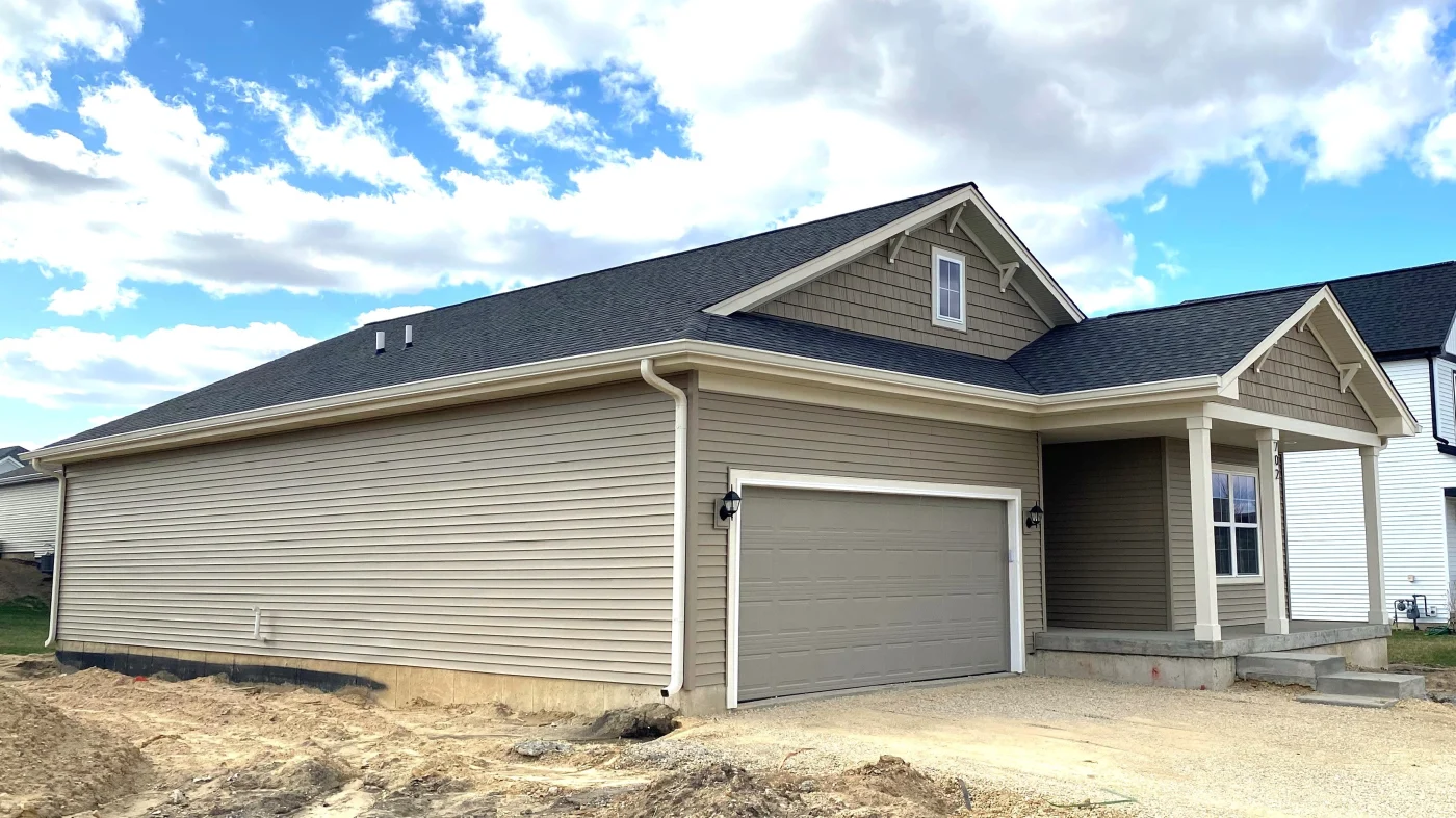Side view of custom Illinois home with light gray siding, white frame replacement windows, and a large garage with a gray door