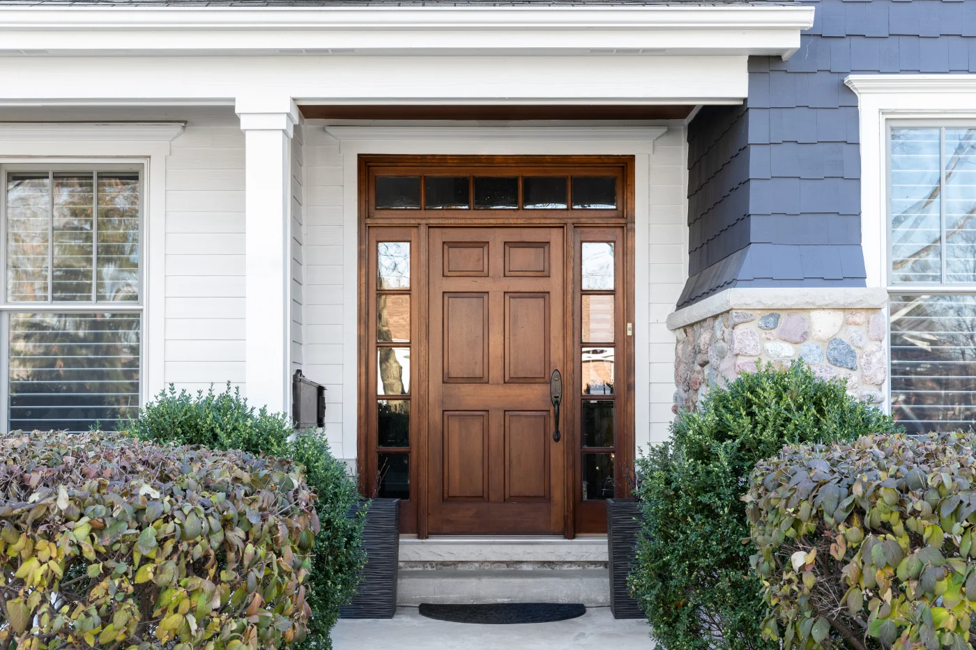 Wood front door on a blue and white house
