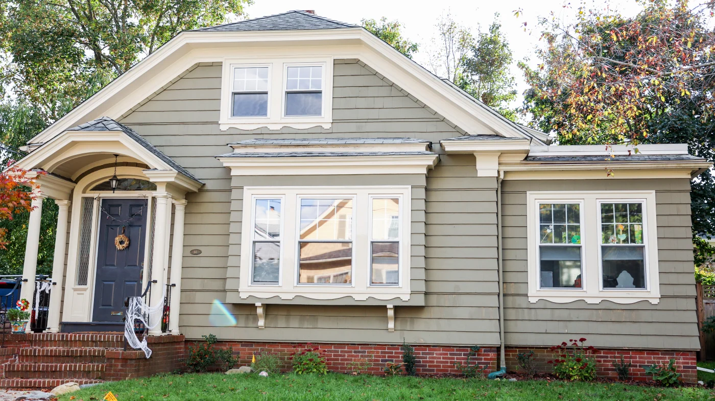 Home with grey siding and lots of different windows with black entry door and asphalt shingle roofing