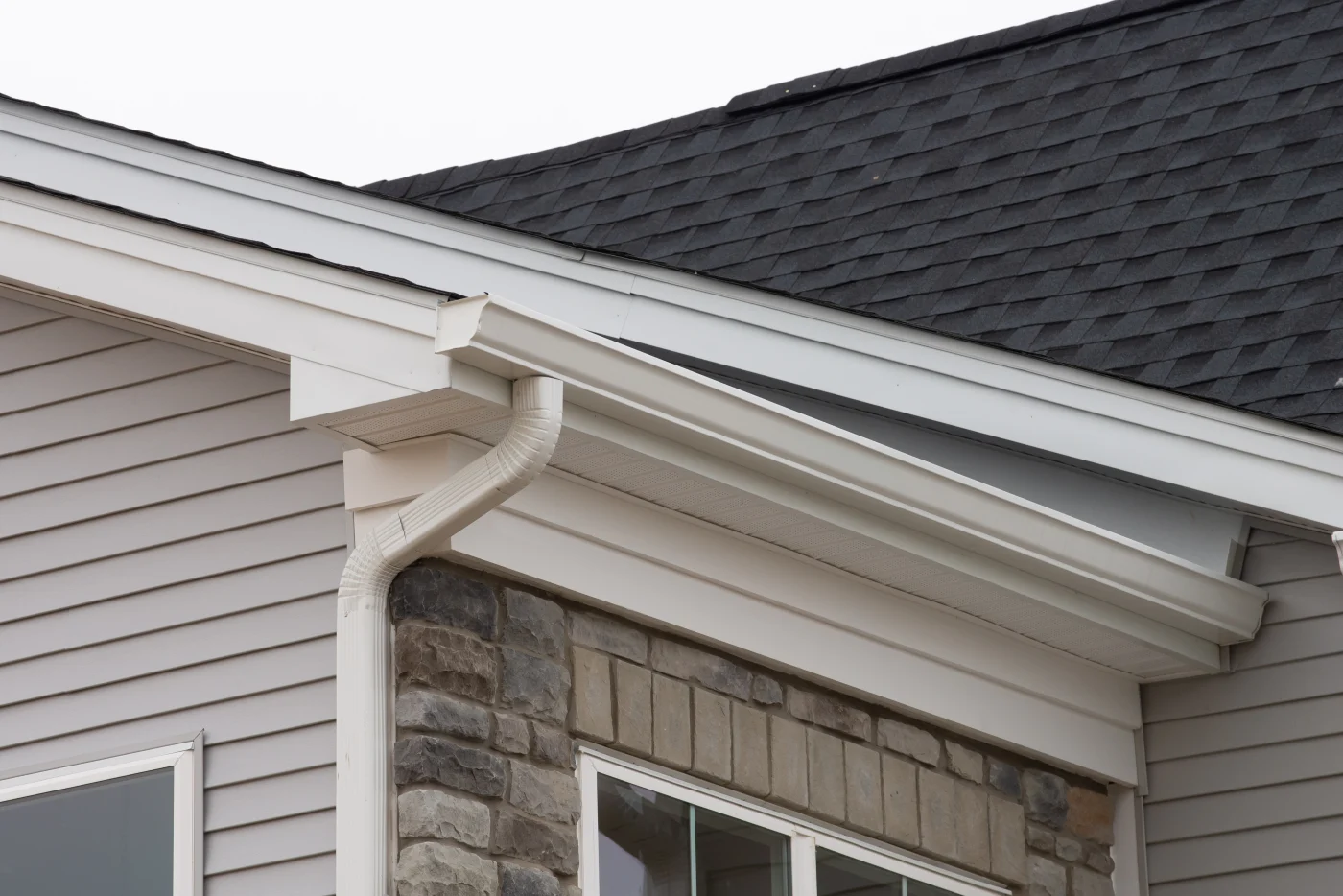 Image of white gutters on a house with stone siding