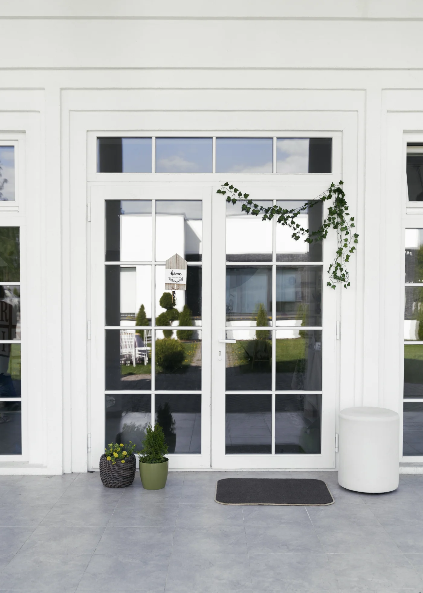 The image features a white fiberglass-sided home with a white framed double door.