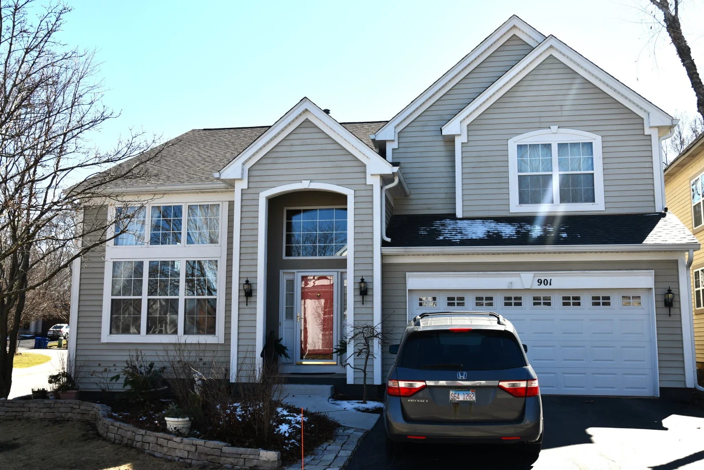 This image features a two-story home with a vehicle in the driveway and a well-installed white gutter system.