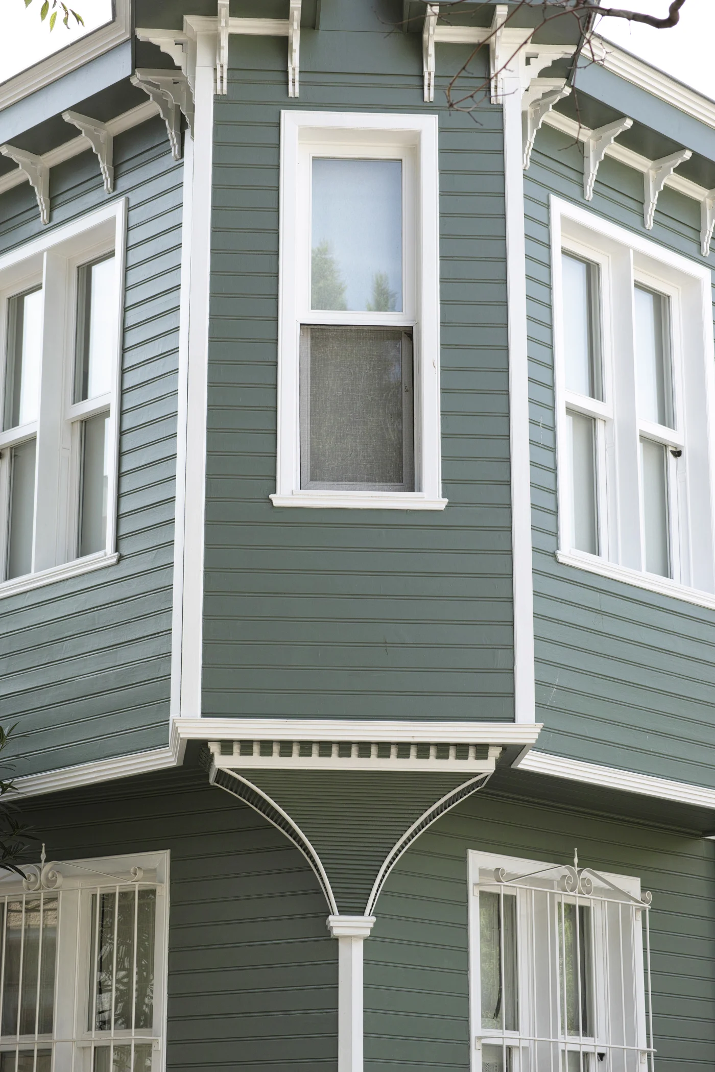 The image features a beautiful green home with white framed windows.