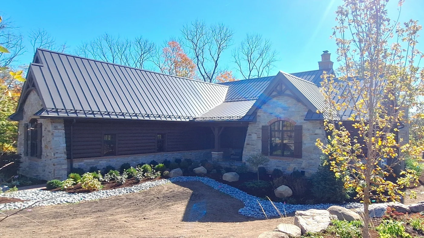 Home with log and stone siding with steep-sloped metal roofing with a well-kept landscape