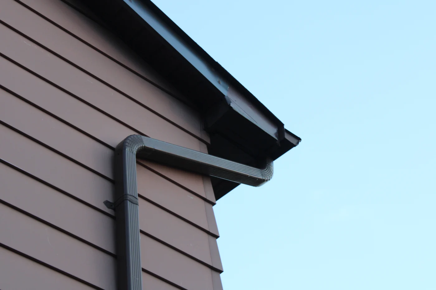 Low-angle image of dark-colored K-style gutters on a house