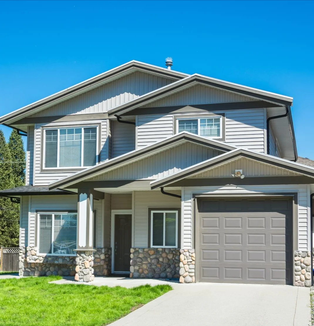 Image of a new two-story house with green lawn and stone veneer siding