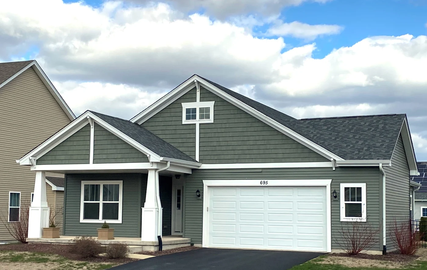 A far-away photo showing a full two-story home with new siding, gutters, and roof.