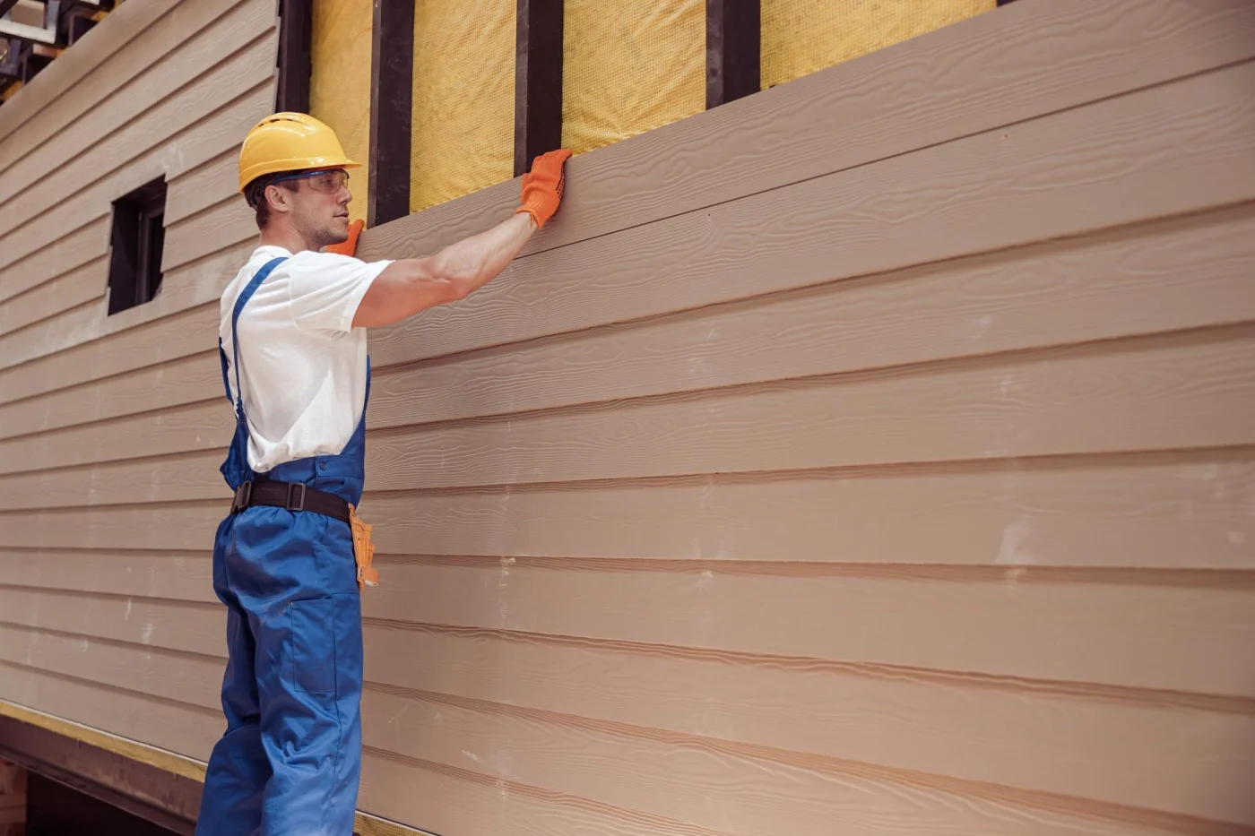 A man carefully installing commercial siding, ensuring precision and quality.