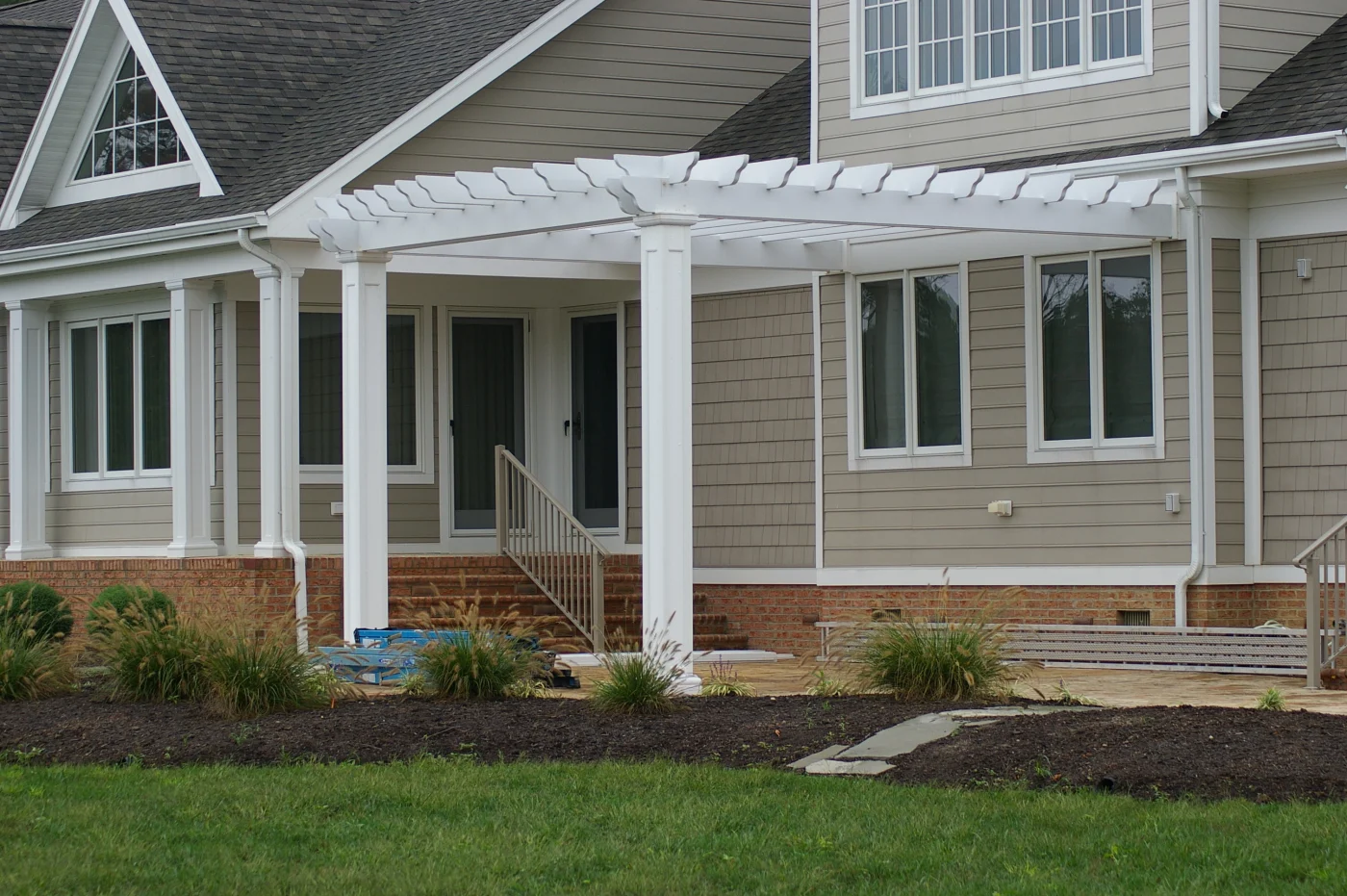 Close-up of a pergola attached to a charming home with gray siding