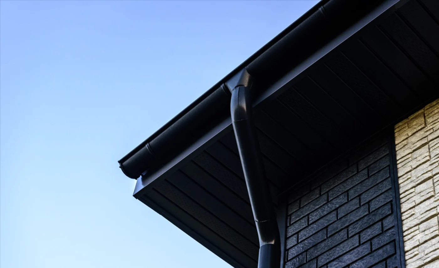 Underside image of black gutters on a house with stone siding