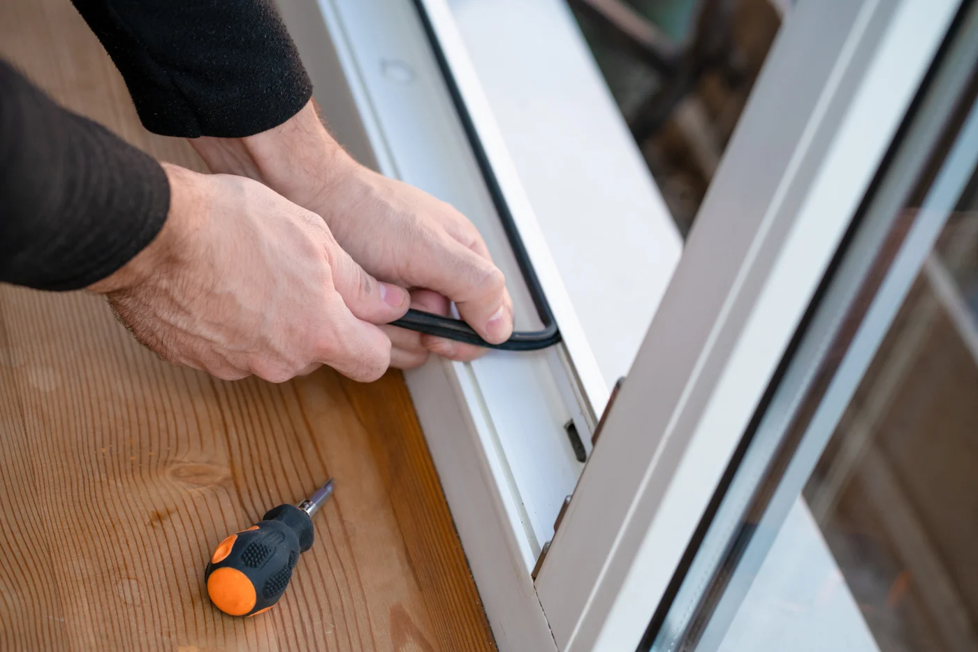 An installer carefully applies weatherstripping to replacement windows