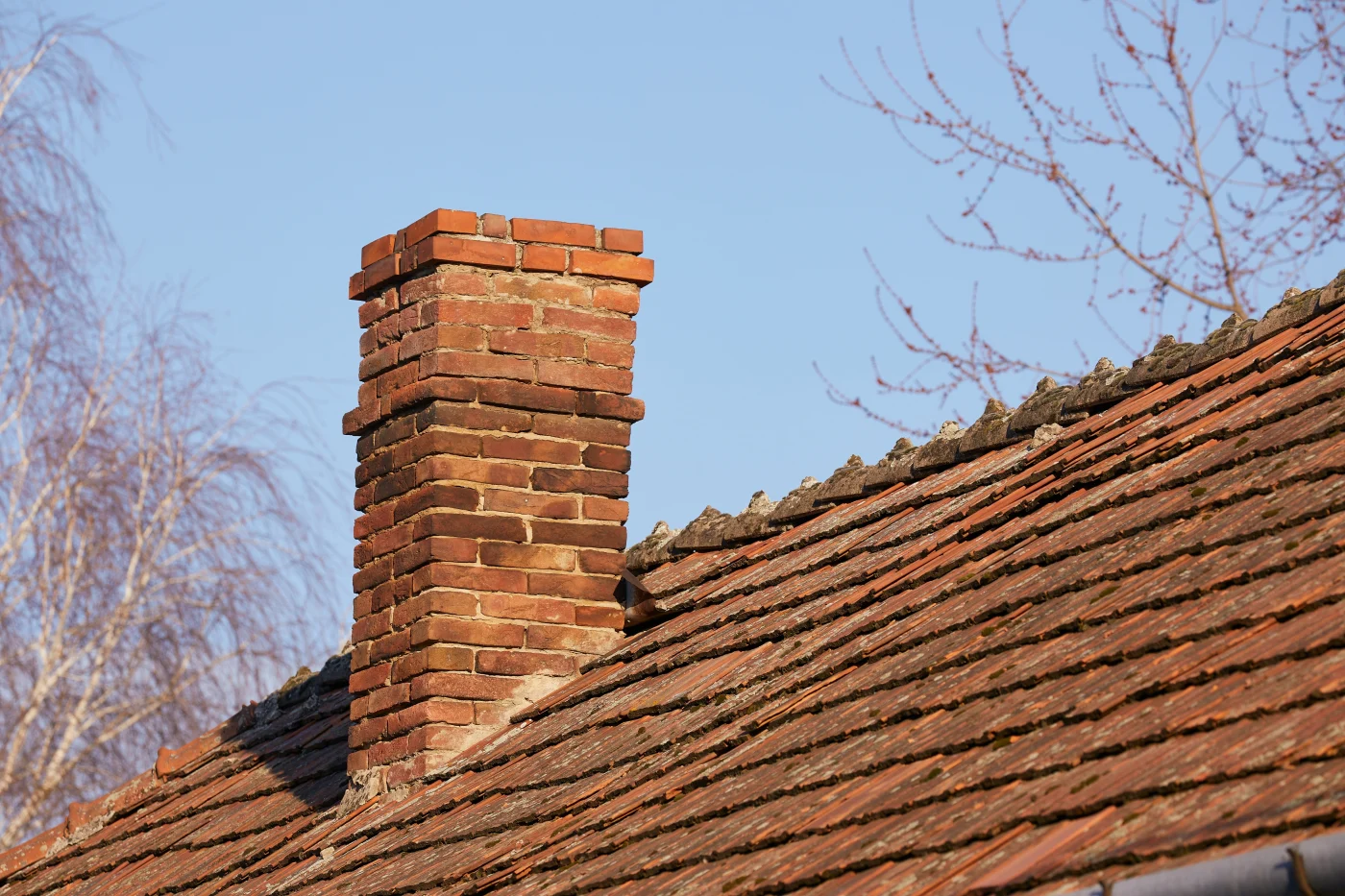 Small Roof Damage Issues Can Become Big, Expensive Problems A close up on a degraded residential roof, where the wood shakes are very old, sagging and neglected, along with the chimney with no flashing.