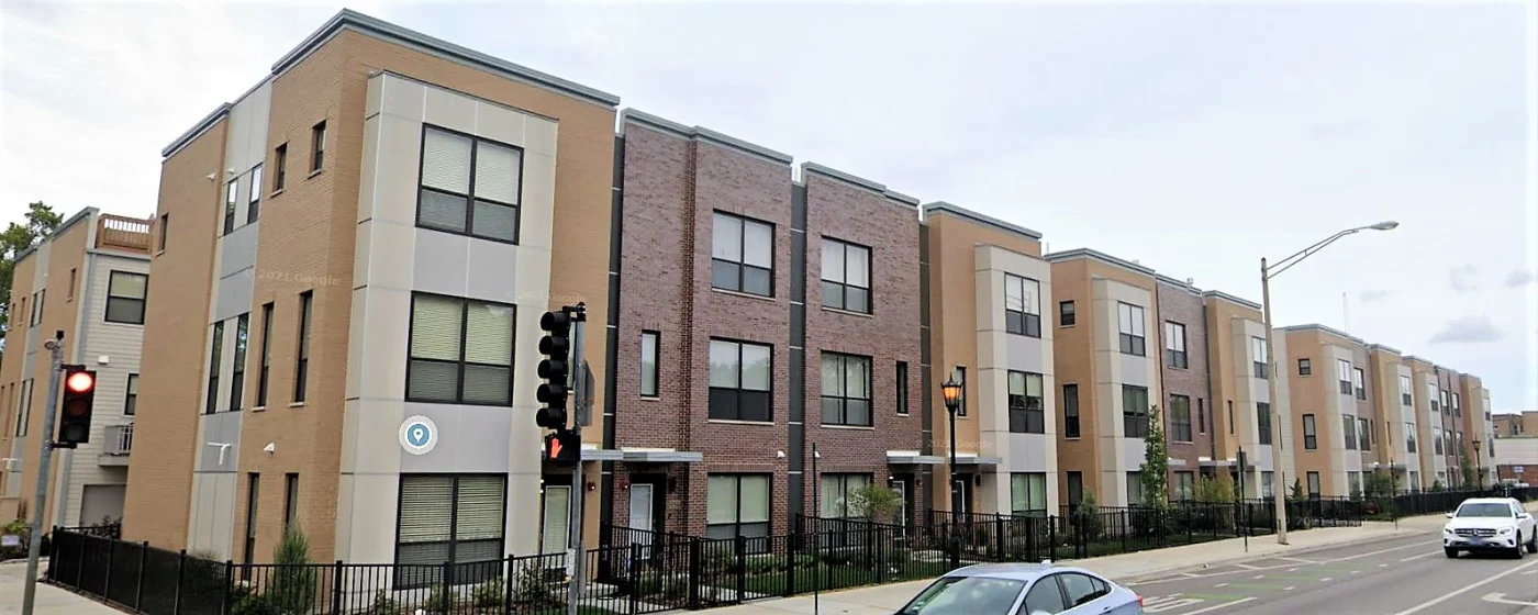 Image of an apartment complex with cars parked in front of it
