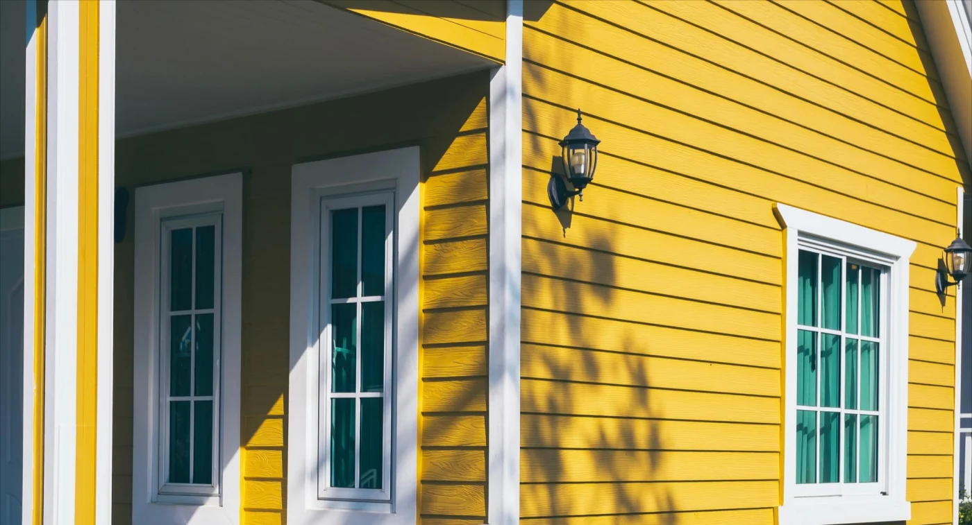 Image of a house with yellow siding and white windows