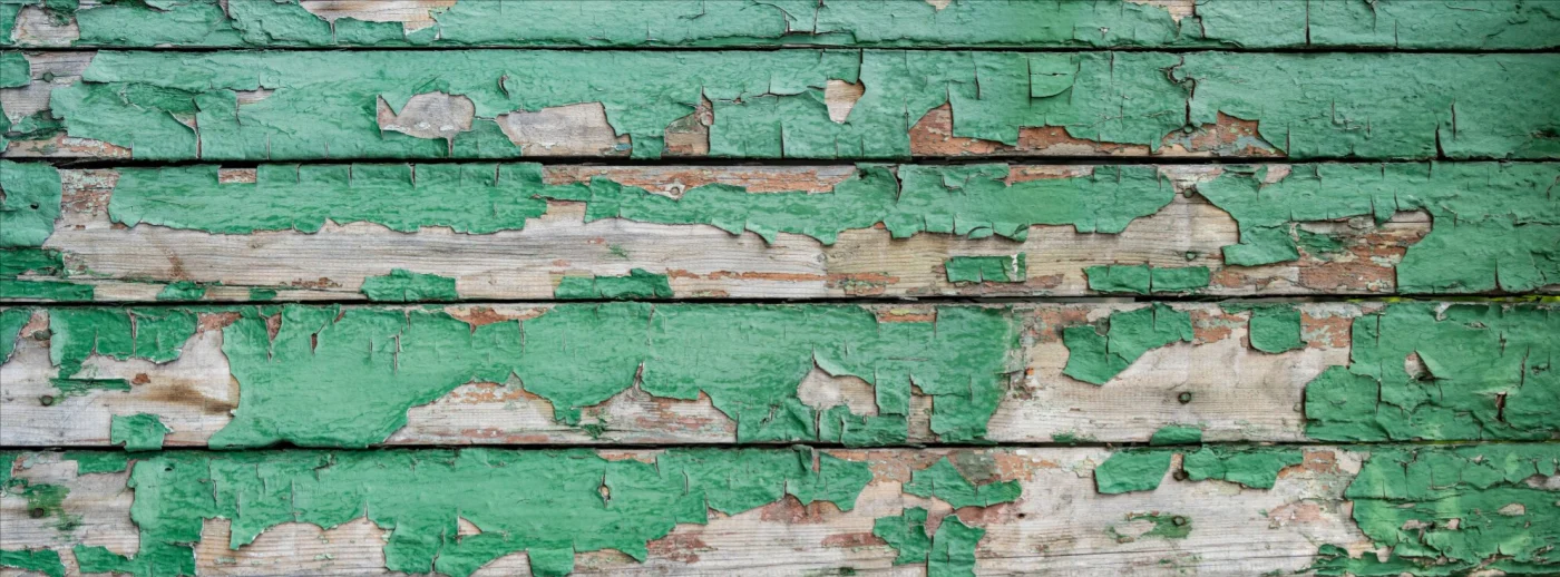 Close-up image of peeling, green siding on a house