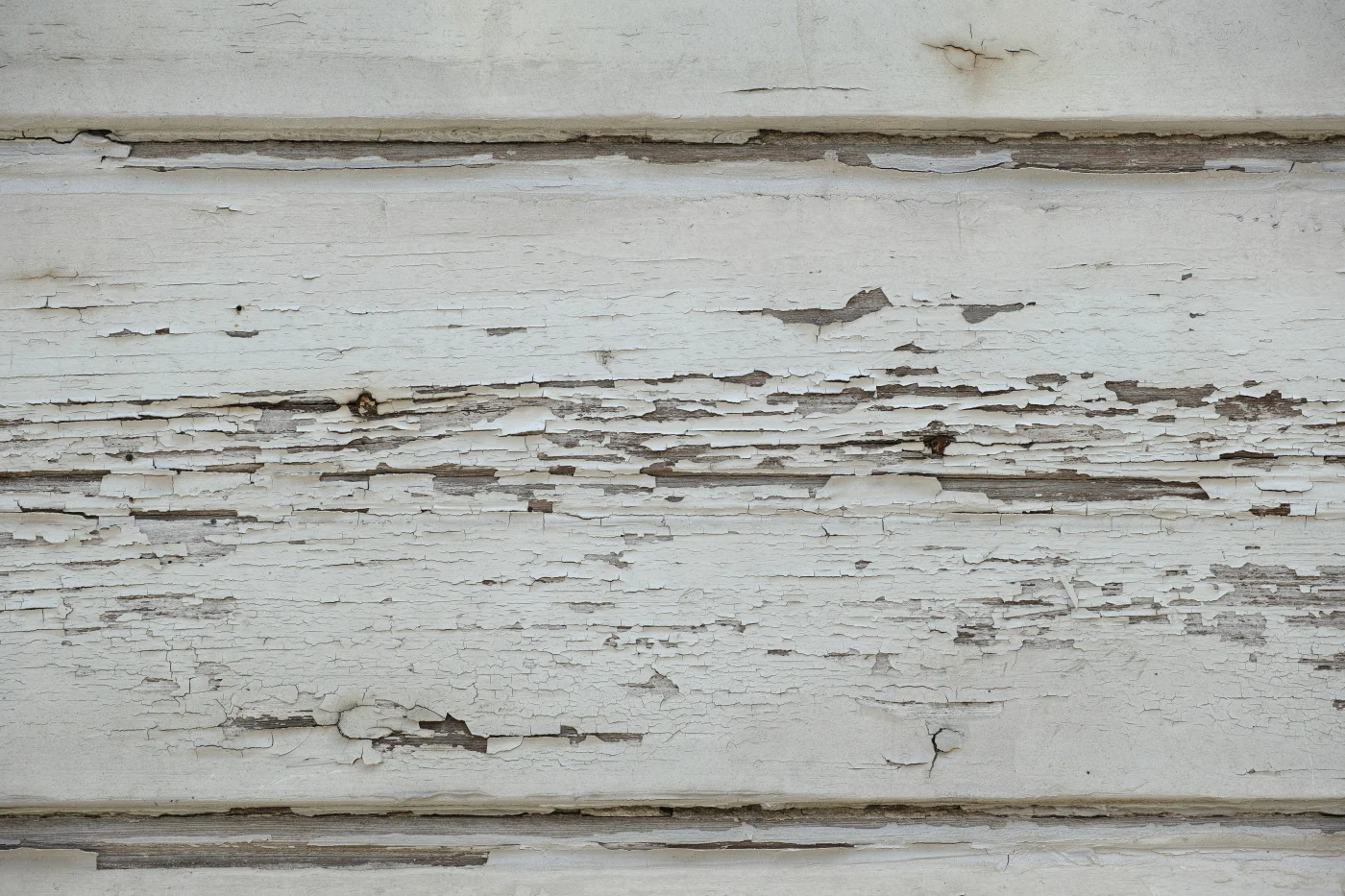 Image of old, peeling white siding on a house