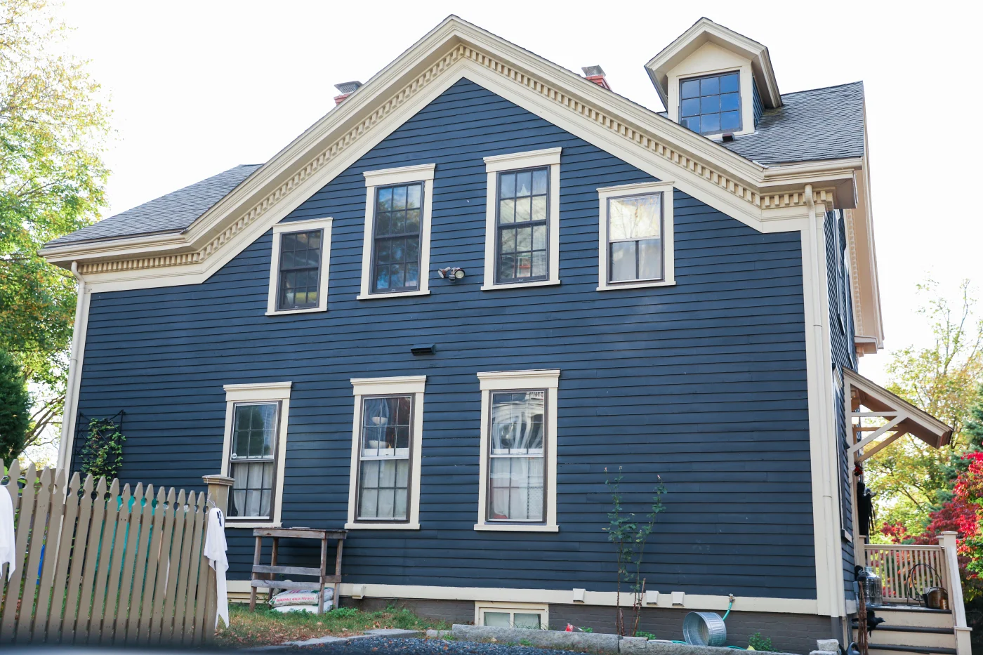 The image features a 2-story house with darker blue siding and white framing around the windows. The siding looks like it was newly installed.
