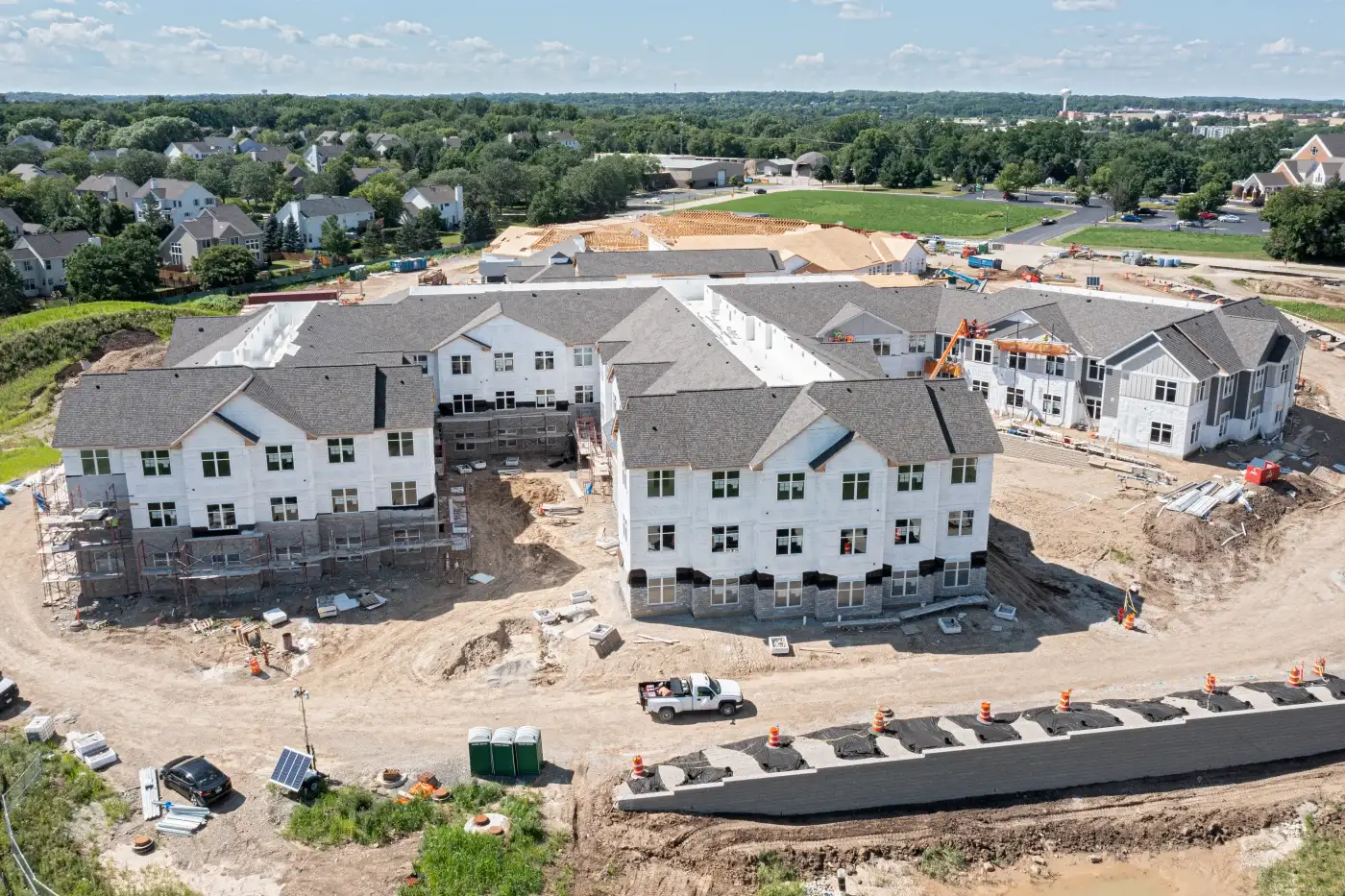 The Benefits Of Being An Apex Exteriors Employee In The Chicagoland Area A large Chicagoland construction site with a complex of multi-family housing units being built, with the framing done, and Apex Exteriors crews working on both new roofing and siding systems.