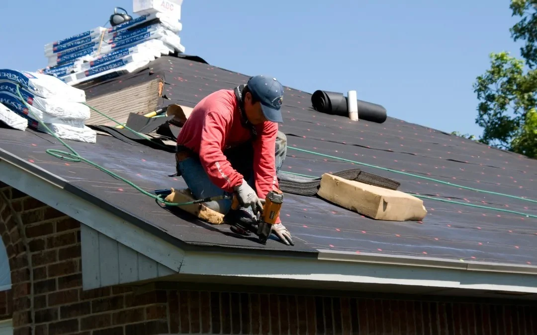 A thoughtful roofer carefully repairs a residential roof.