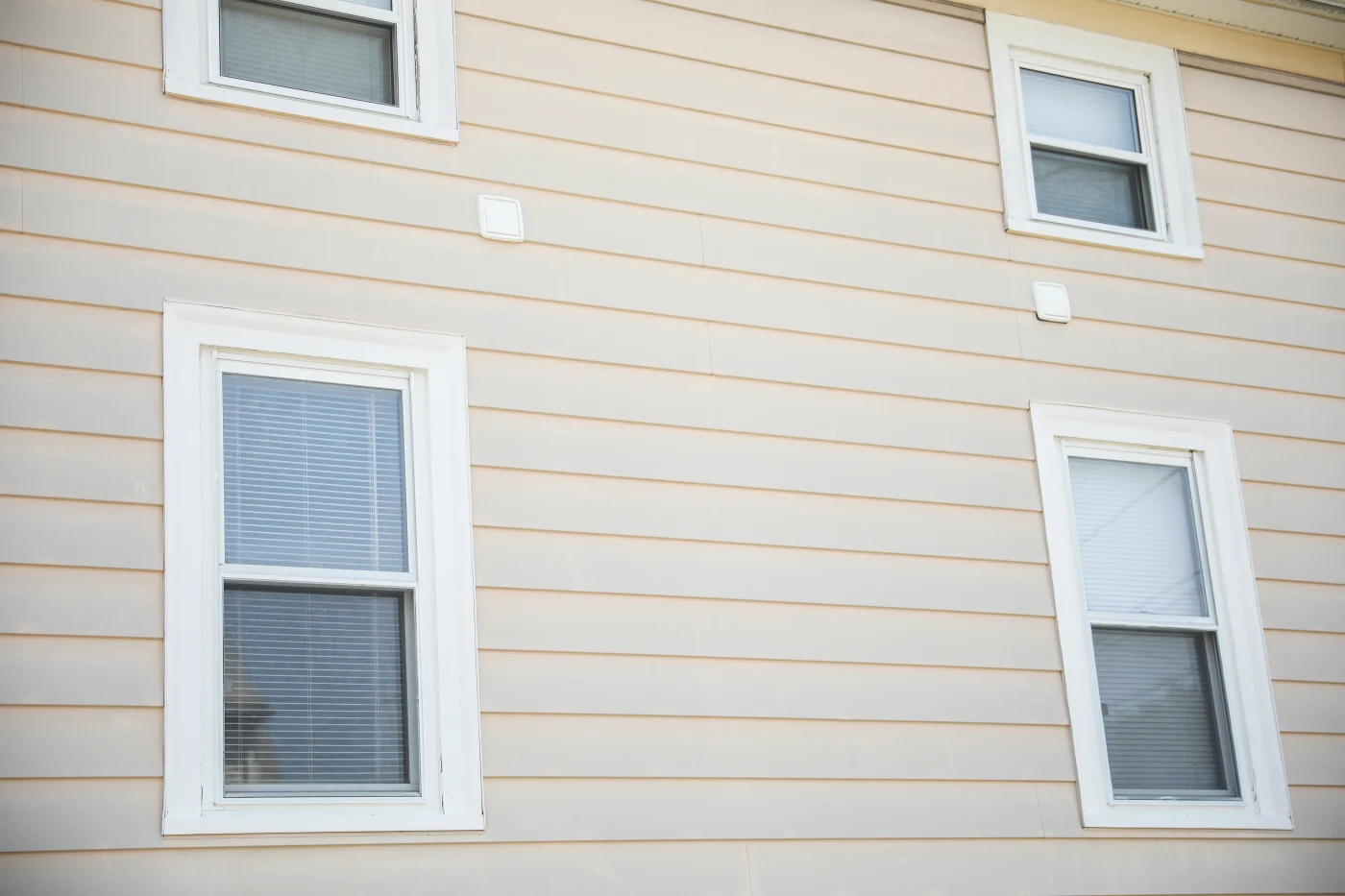 A worker installing new beige siding on a new construction home in Glen Ellyn, IL.