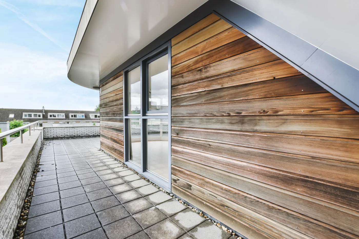 A lovely, wooden shake-sided home with a slanted roof. There is a porch surrounding the house.