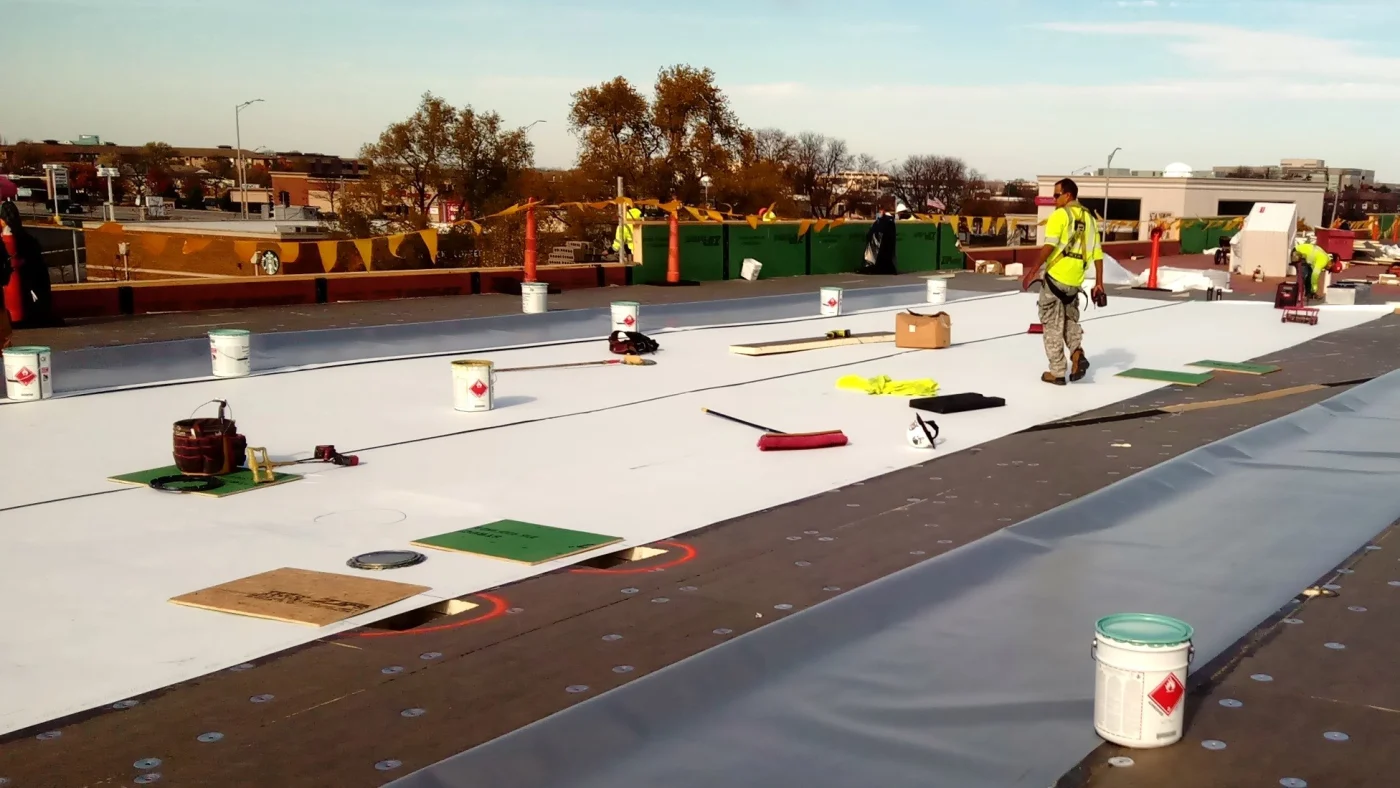 Roofer on top of a commercial building installing a new roof in Bloomingdale, IL by Apex Exteriors.