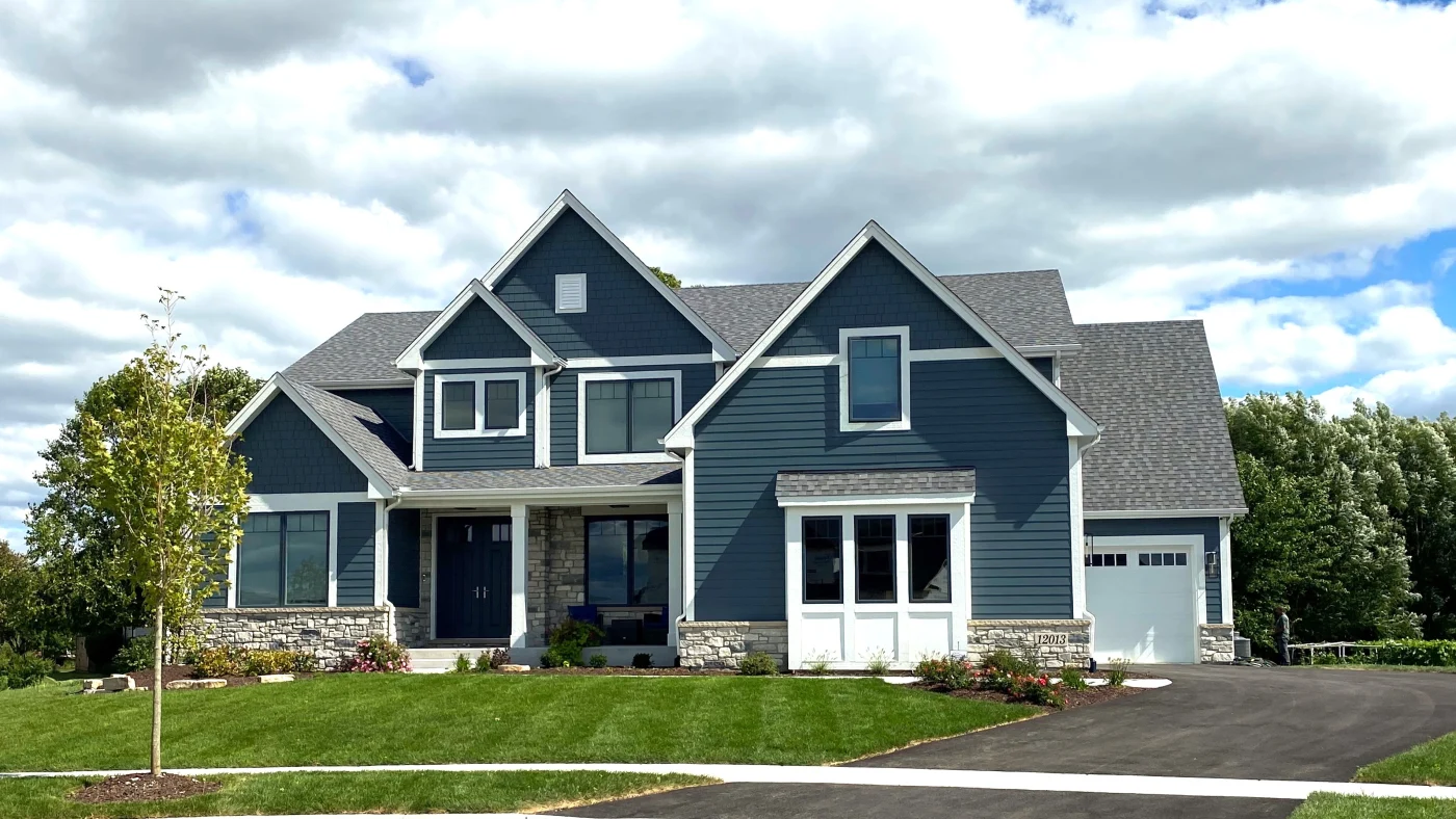 The front of a large home with white trim and blue siding in Elmhurst, IL by Apex Exteriors.