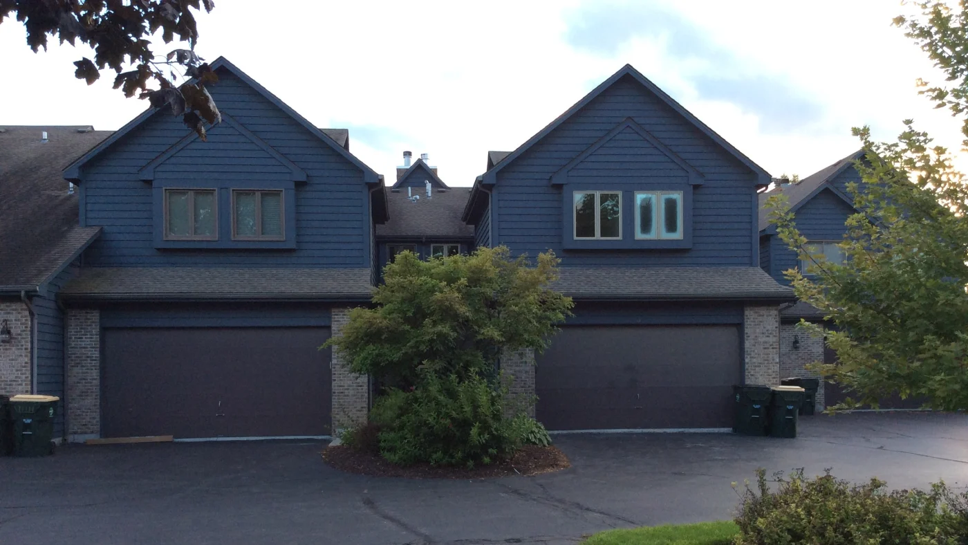 The front of houses in a neighborhood with blue and brown siding in Lombard, IL by Apex Exteriors.