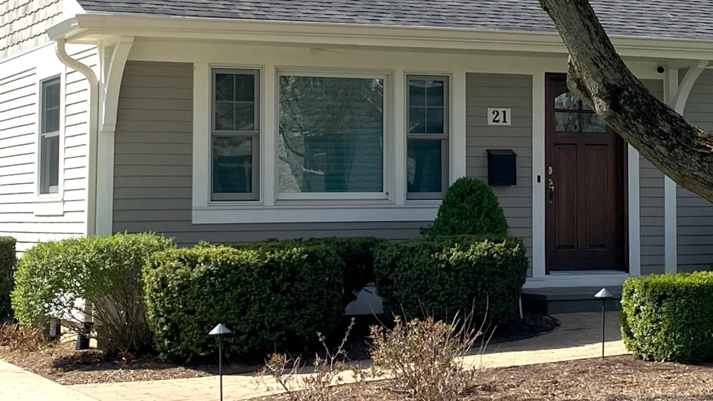 A house with light gray siding and a brown door in Lombard, IL by Apex Exteriors.
