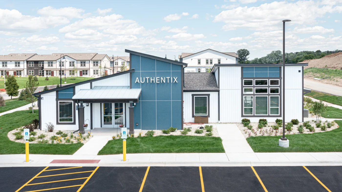 The front of a commercial building in an apartment complex with white and blue siding in Wheaton, IL by Apex Exteriors.