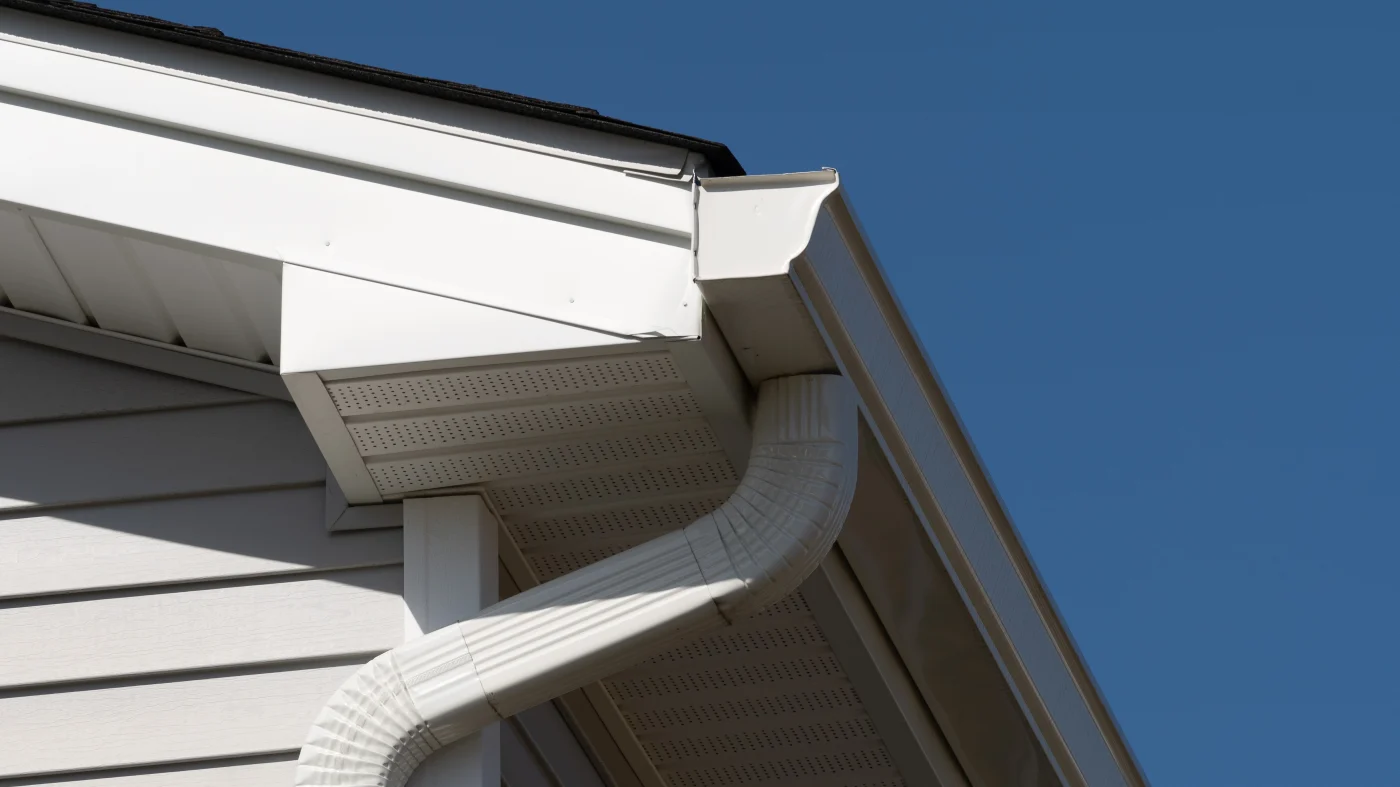 A close-up of white gutters on a house with off-white siding in Bloomingdale, IL by Apex Exteriors.