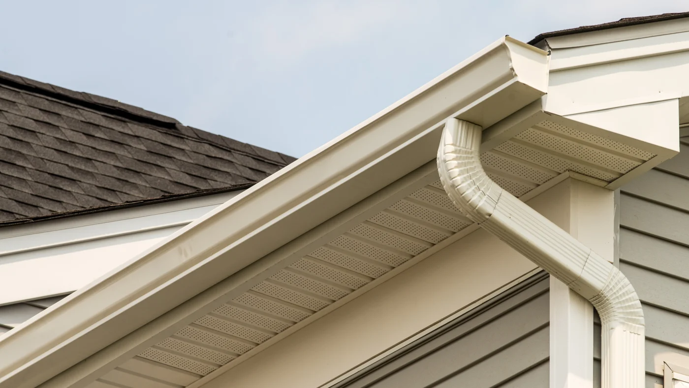 A close-up of beige gutters on a house with light gray siding in Elmhurst, IL by Apex Exteriors.