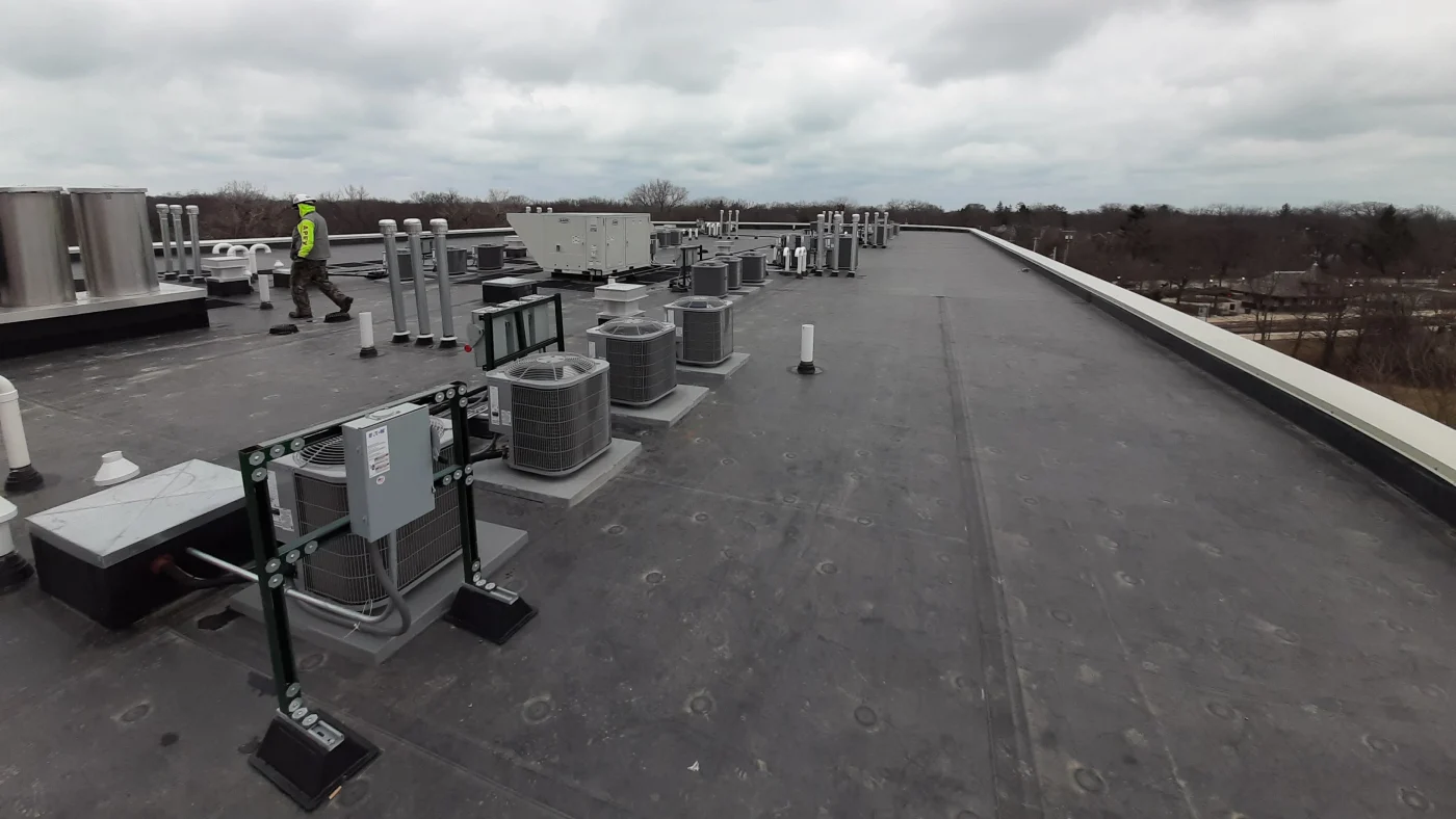 The top of a roof with a roofing crew finishing installation in LaGrange, IL by Apex Exteriors.