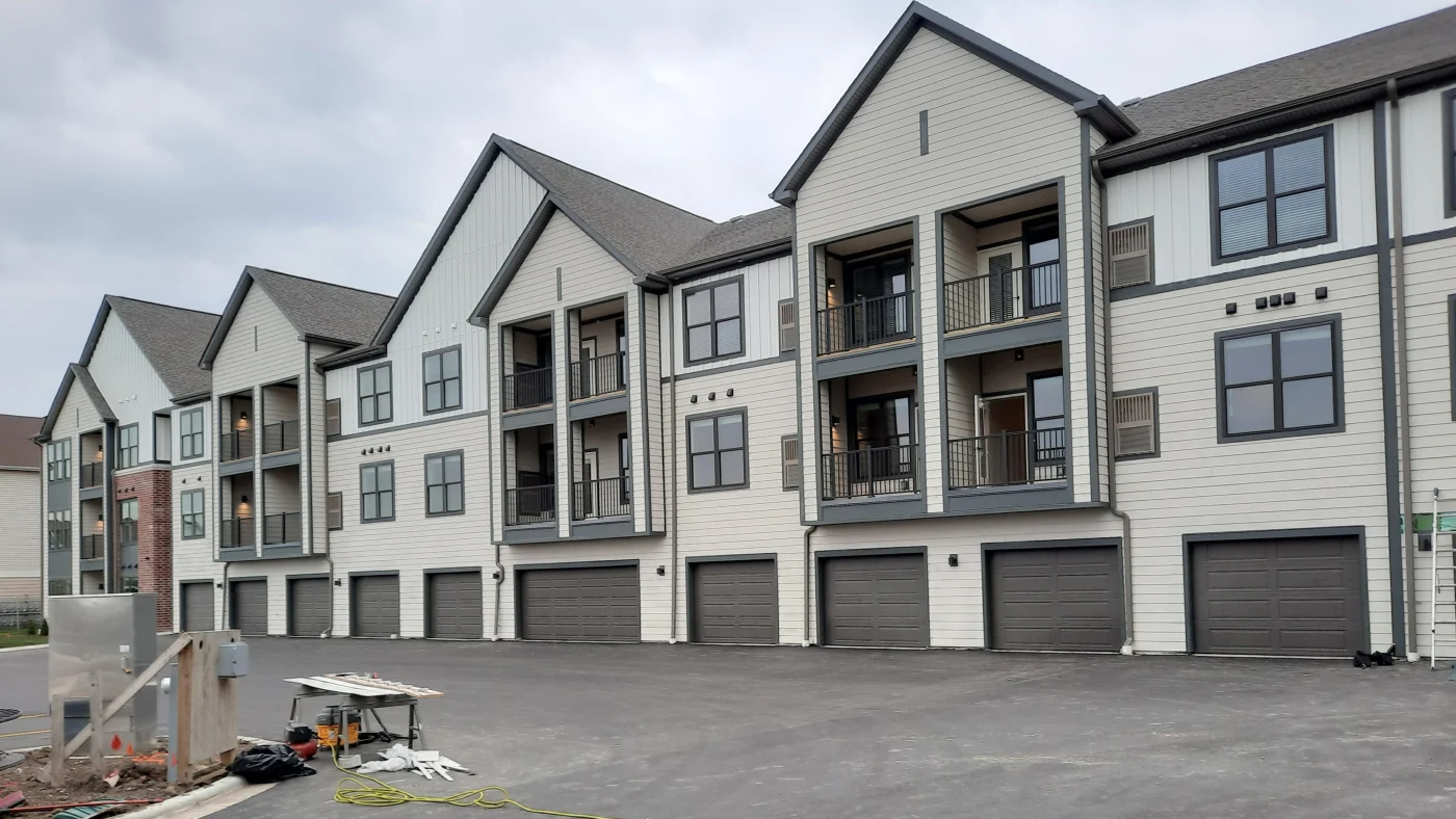 The front of an apartment building with beige siding in Elmhurst, IL by Apex Exteriors.