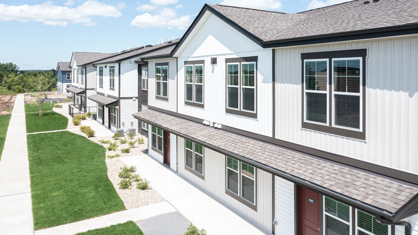An angled view of a row of apartment buildings with white siding in Wheaton, IL by Apex Exteriors.