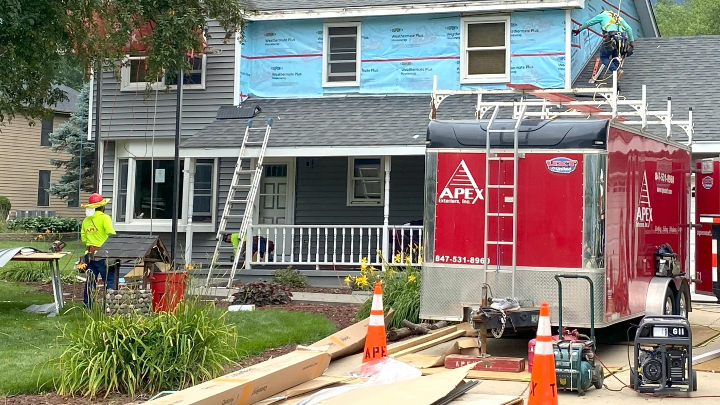 A siding installation crew is replacing the siding on a home in Bloomingdale, IL by Apex Exteriors.