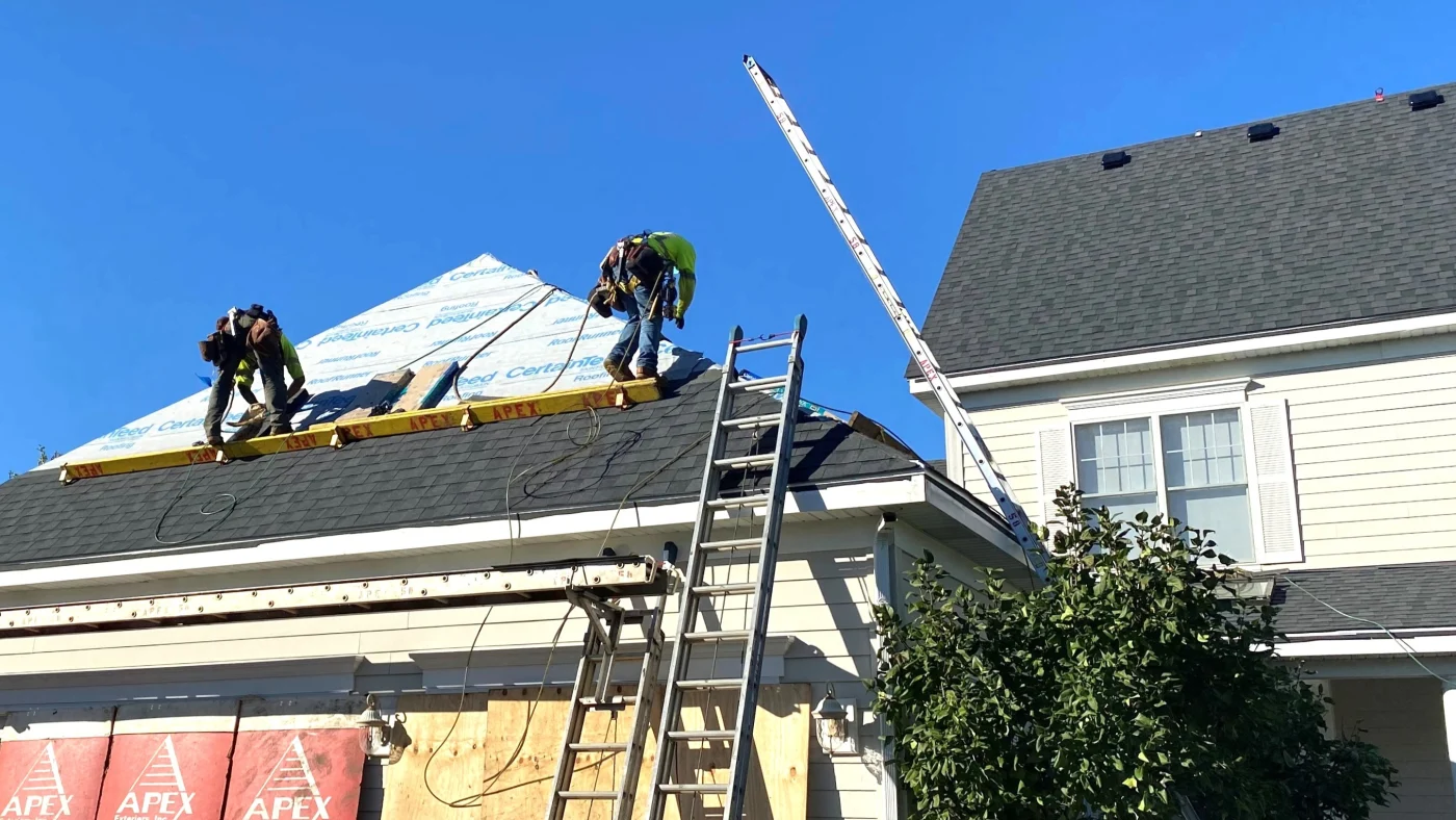Two crew members are up on a rooftop replacing the roof of a home in Lombard, IL by Apex Exteriors.