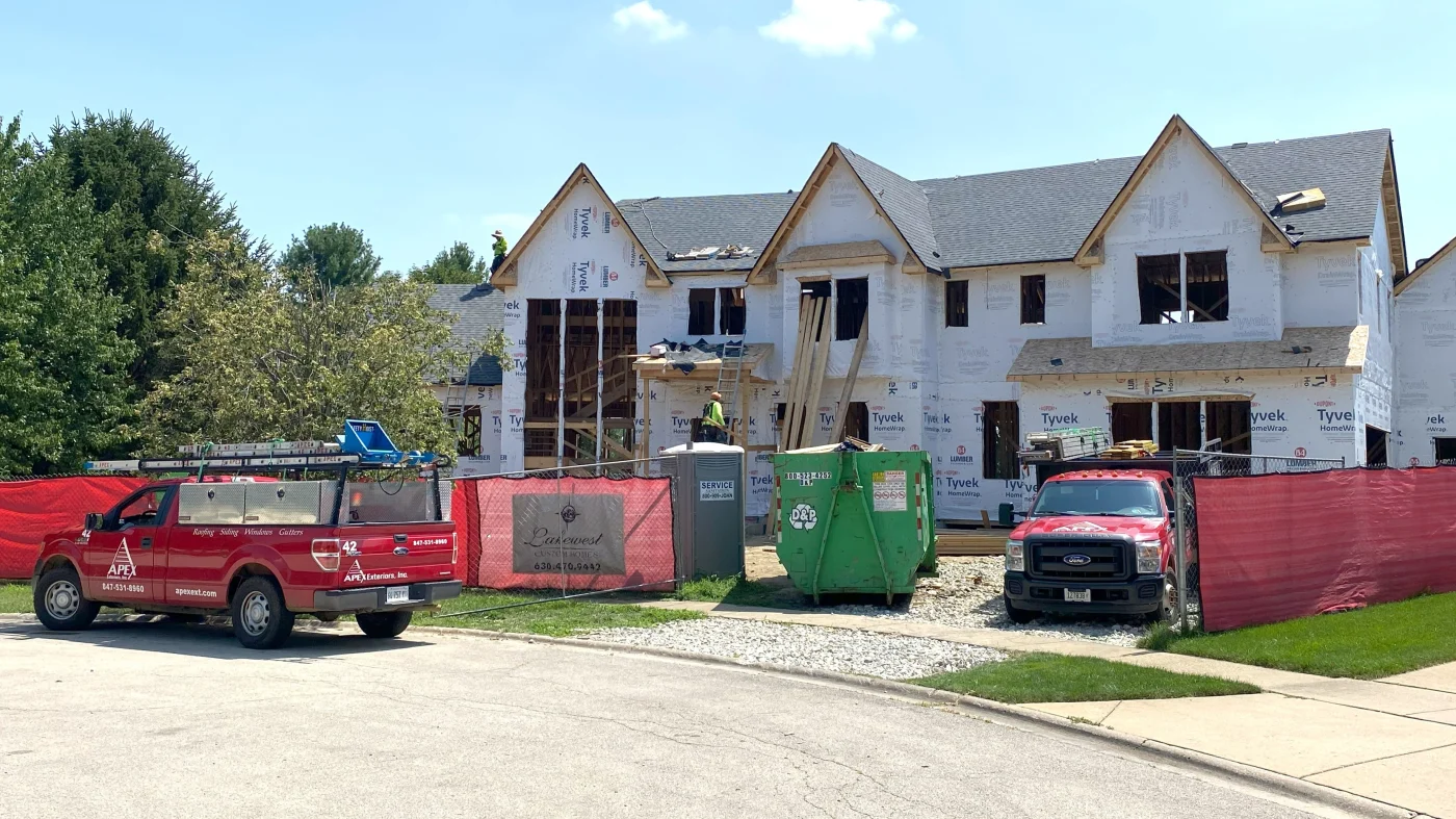 Apex Exteriors trucks are parked in front of a new home under construction in LaGrange, IL by Apex Exteriors.
